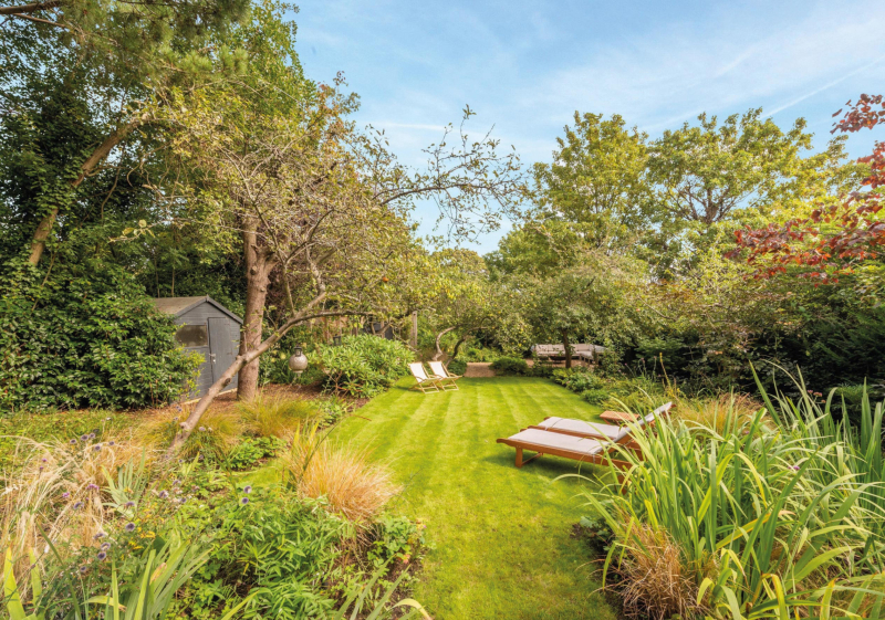 Nestled beneath mature trees lies a secluded lawn