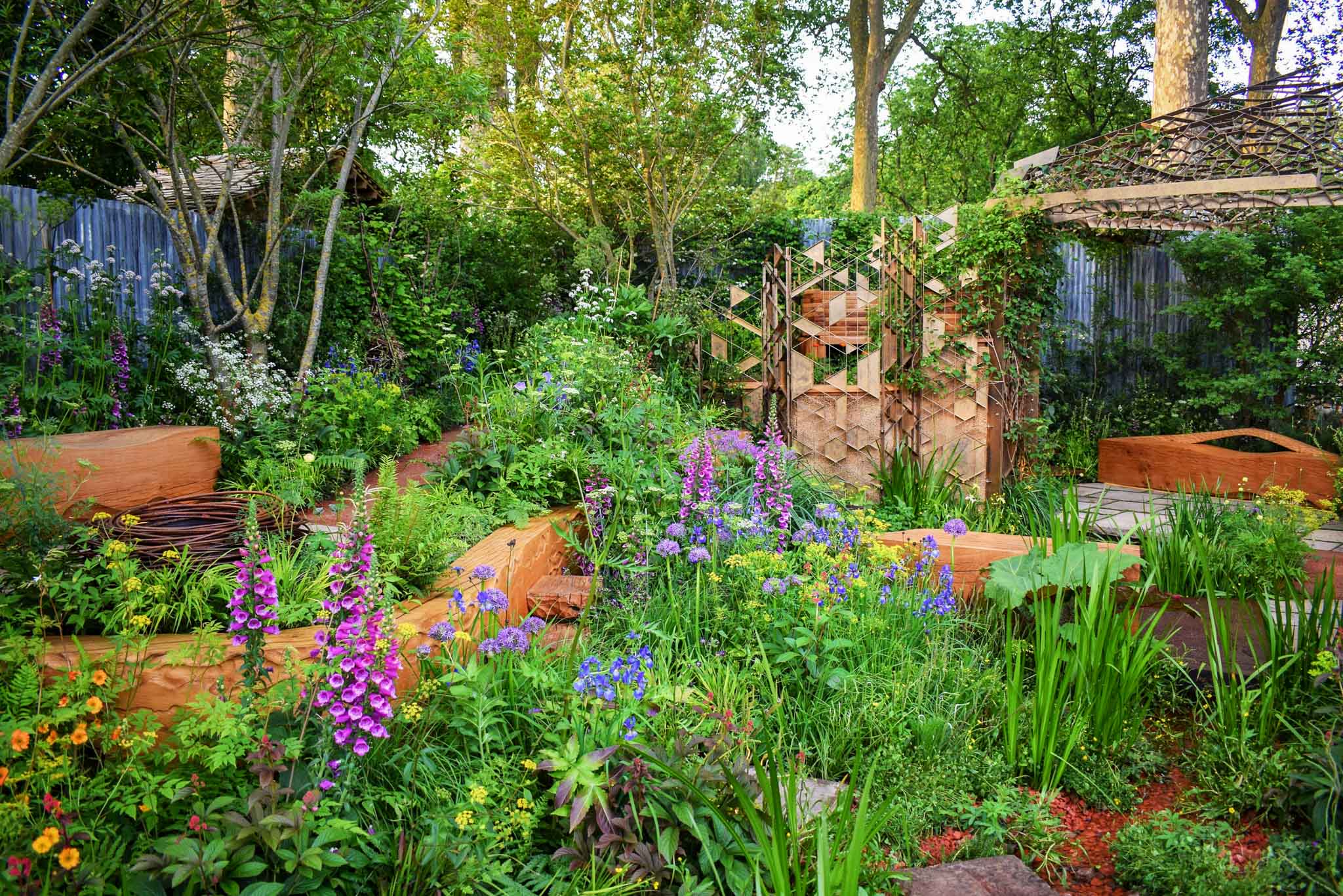 Garden building and colourful vibrant planting in the Octavia Hill Garden at RHS Chelsea Flower Show 2024. Designed by Ann-Marie Powell Gardens